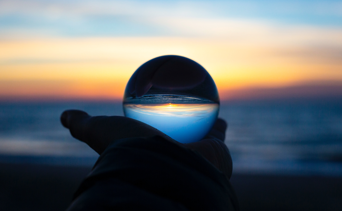 A person holding a crystal ball looking out onto the ocean