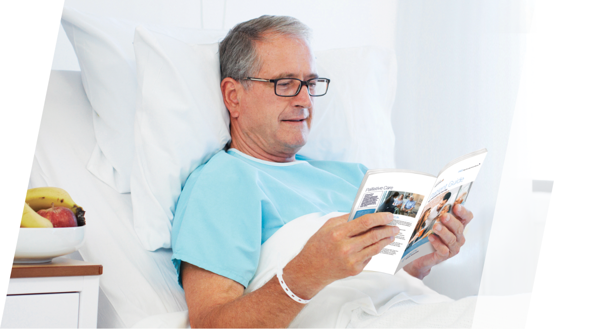 Patient in bed reading a hospital patient guide.