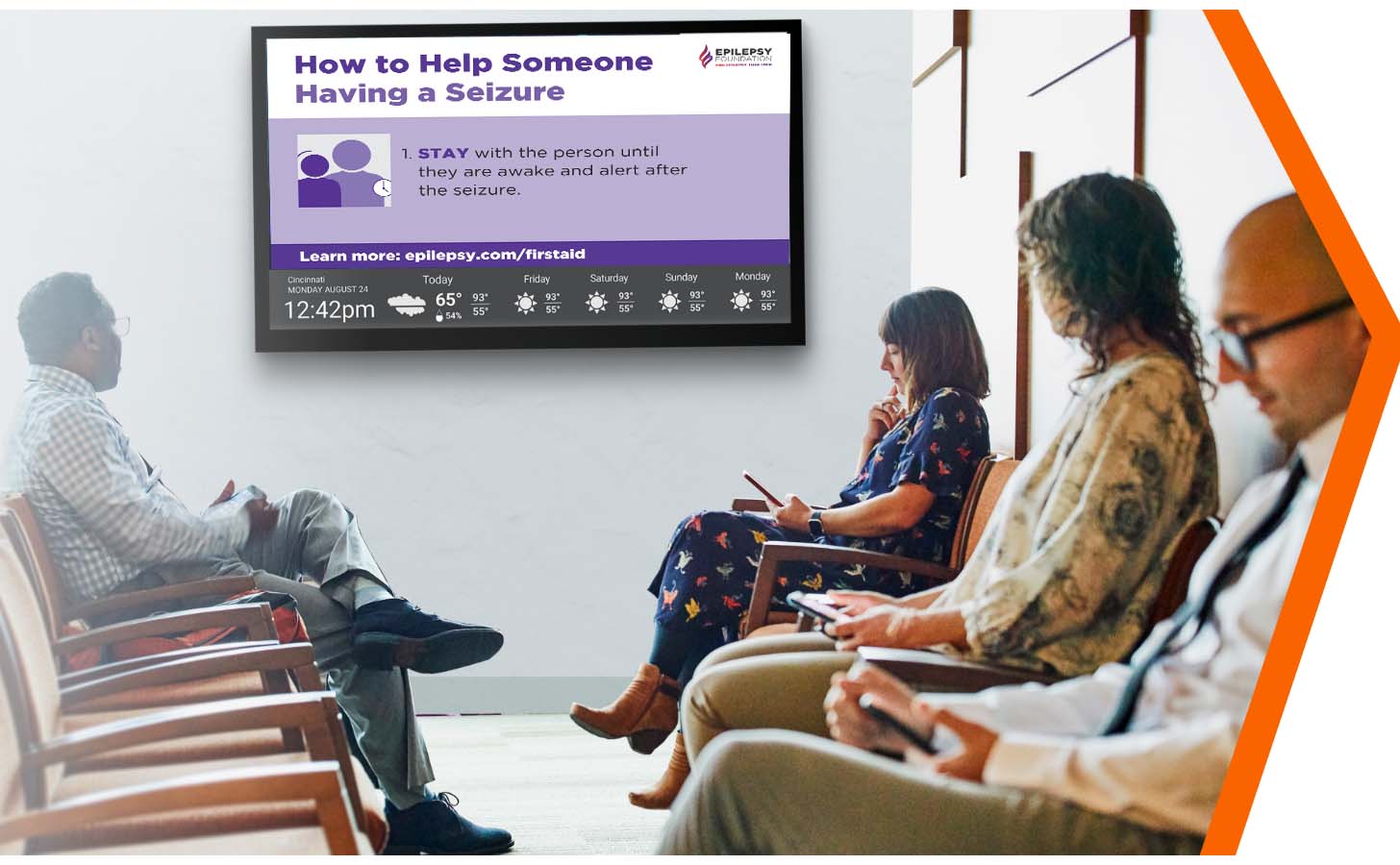 Group of patients sitting in a waiting room looking on to a screen on the wall with content about seizure safety