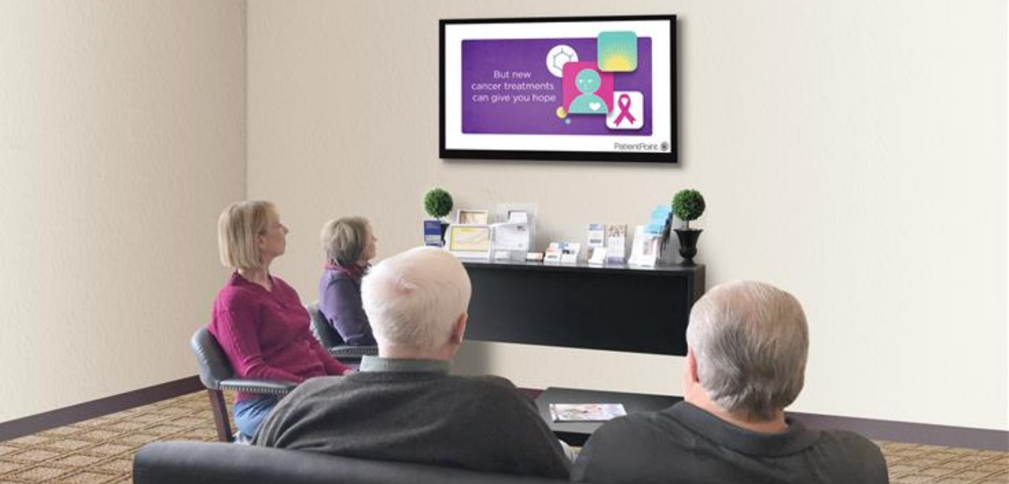 Patients viewing waiting room screen with oncology content
