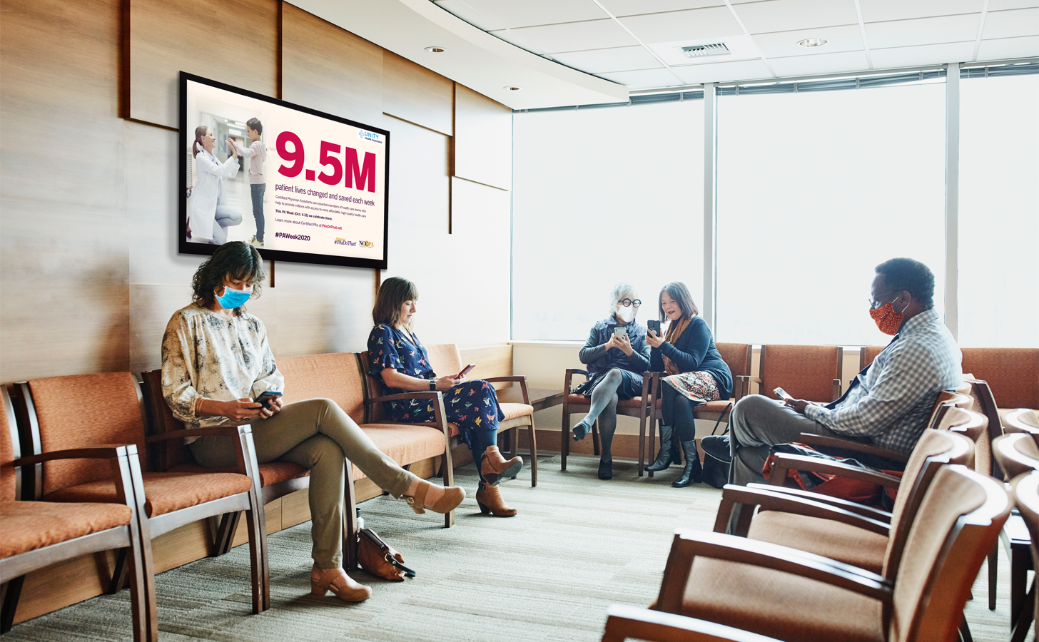 A group of patients sit in a waiting room featuring a digital screen with content celebrating physician assistants.